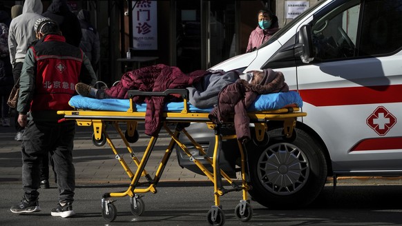 An elderly woman is wheeled into the fever clinic at a hospital in Beijing on Sunday, Dec. 11, on a stretcher.  11, 2022. Faced with surge in COVID-19 cases, China is setting up more intensive care facilities…