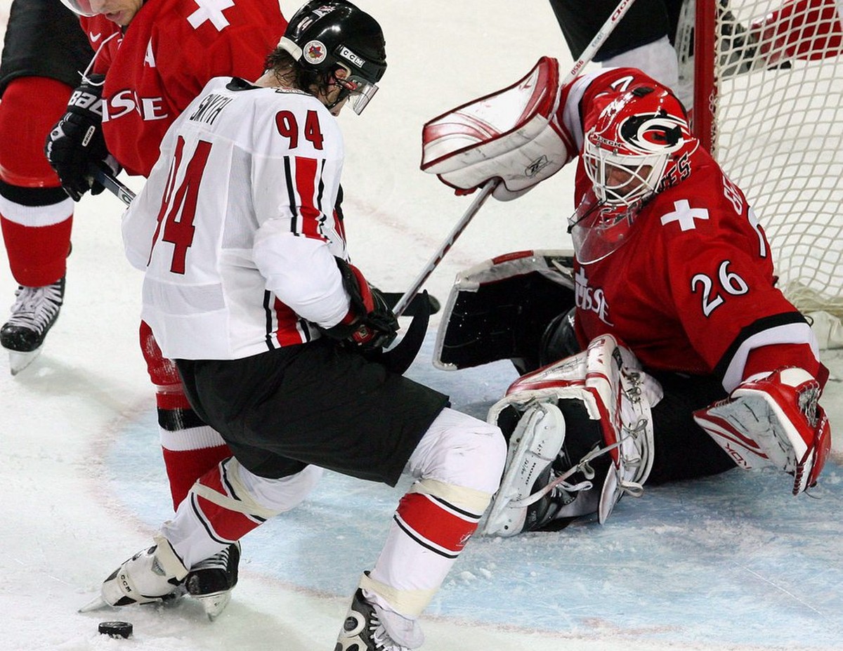 Switzerland's Martin Gerber (R) stop Canada's Ryan Smith (C) in front of the net during the Men's Preliminary Round game between Canada and Switzerland at the Turin 2006 Winter Olympic  ...