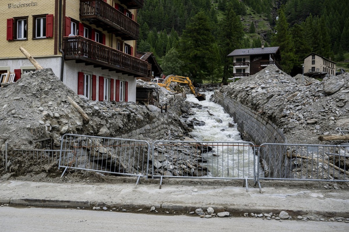 Une pelleteuse enleve des gravats dans le lit de la riviere Triftbach dans le village haut-valaisan ensevelie ce week-end par une lave torrentielle le mardi 2 juillet 2024 a Saas-Grund. (KEYSTONE/Jean ...