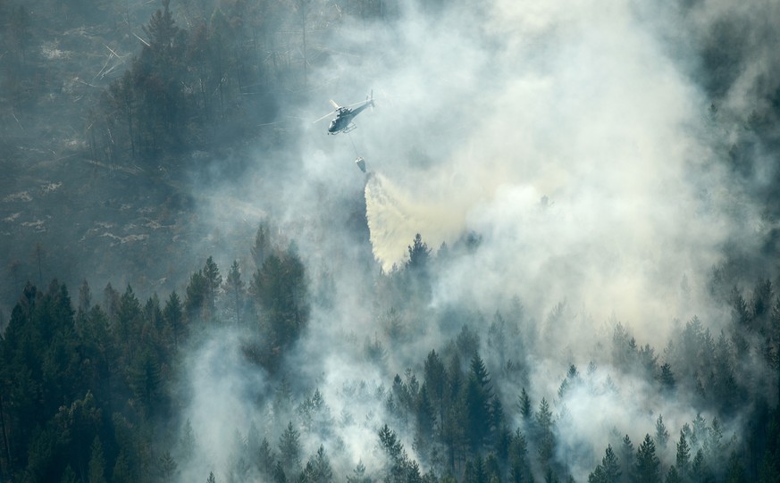 epaselect epa06897098 A firefighting helicopter drops water over the fire in Ljusdal, Sweden on 18 July 2018. The fire is one of 40 wildfires in Sweden due to the dry weather. EPA/Maja Suslin SWEDEN O ...