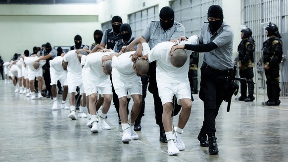 epaselect epa11969342 A handout photo made available by the Presidency of El Salvador shows guards at the Terrorism Confinement Center (Cecot) transferring alleged members of the criminal gang known a ...
