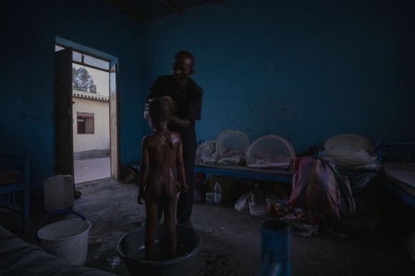 Tigrayan refugee Abraha Kinfe Gebremariam bathes his 5-year-old son, Micheale, early in the morning in their shelter in Hamdayet, eastern Sudan, near the border with Ethiopia, on March 21, 2021. (AP P ...