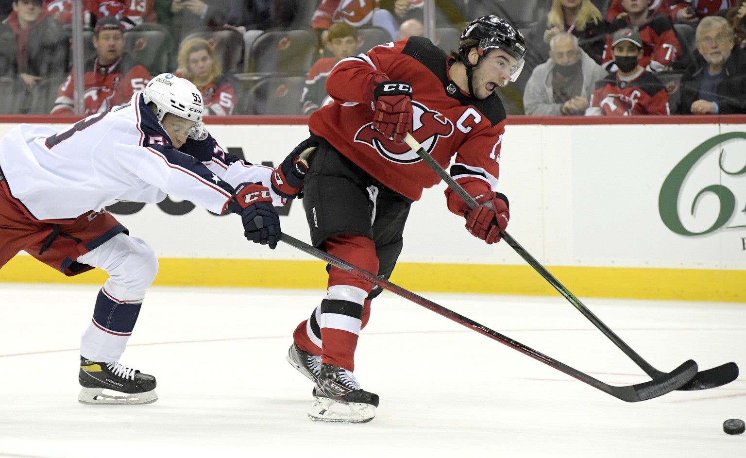 New Jersey Devils center Nico Hischier, right, shoots as he is checked by Columbus Blue Jackets defenseman Gabriel Carlsson, left, during the second period of an NHL hockey game Sunday, Oct. 31, 2021, ...