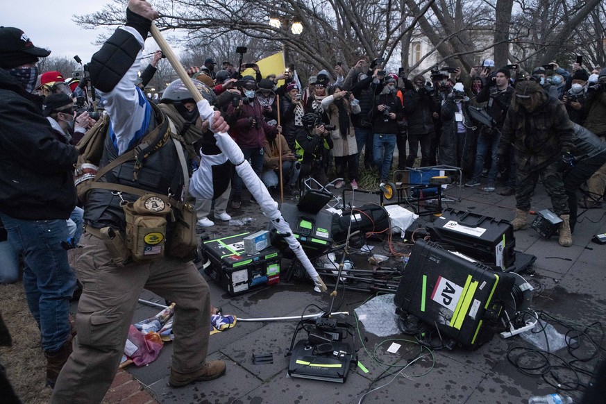 Demonstrators break TV equipment outside the the U.S. Capitol on Wednesday, Jan. 6, 2021, in Washington. (AP Photo/Jose Luis Magana)