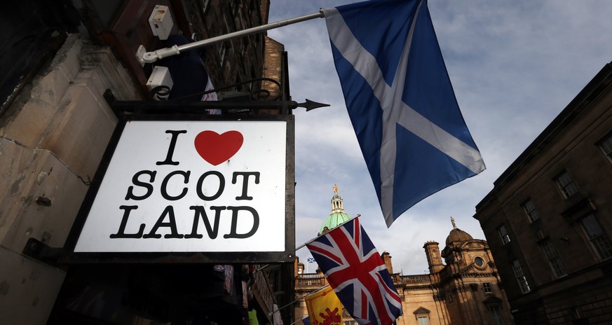 FILE - In this Thursday, Feb. 13, 2014, file photo a Scottish flag and a Union flag fly outside a Scottish memorabilia shop in Edinburgh, Scotland. The British government plans to offer Scotland more  ...