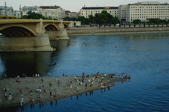 People walk on a sandbar underneath the Danube's Margareth Bridge in downtown Budapest, Hungary, Wednesday Aug. 5, 2026, as the river, which runs through 10 European countries, has receded never- ...