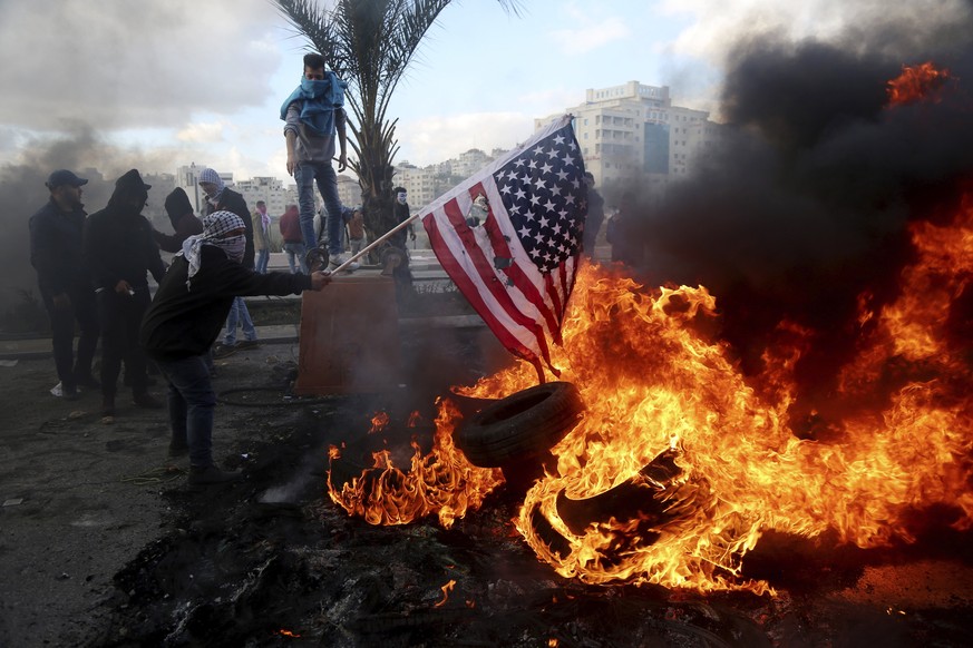 epa06374195 Palestinians protester burn the US flag during clashes with Israeli soldiers following a protest in the west Bank city Ramallah, 07 December 2017. Palestinians announced general strike and ...