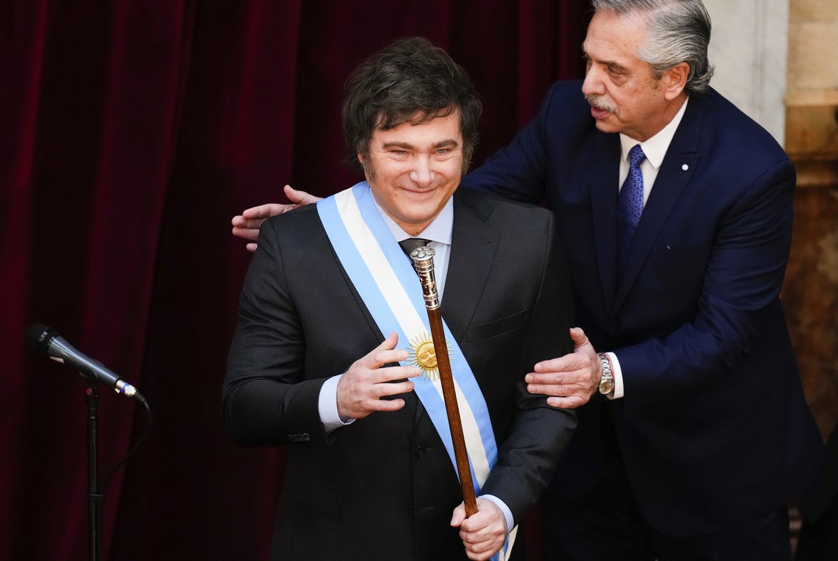 Argentina's outgoing President Alberto Fernandez pats incoming President Javier Milei after handing him the presidential sash at the Congress in Buenos Aires, Argentina, Sunday, Dec. 10, 2023. (A ...