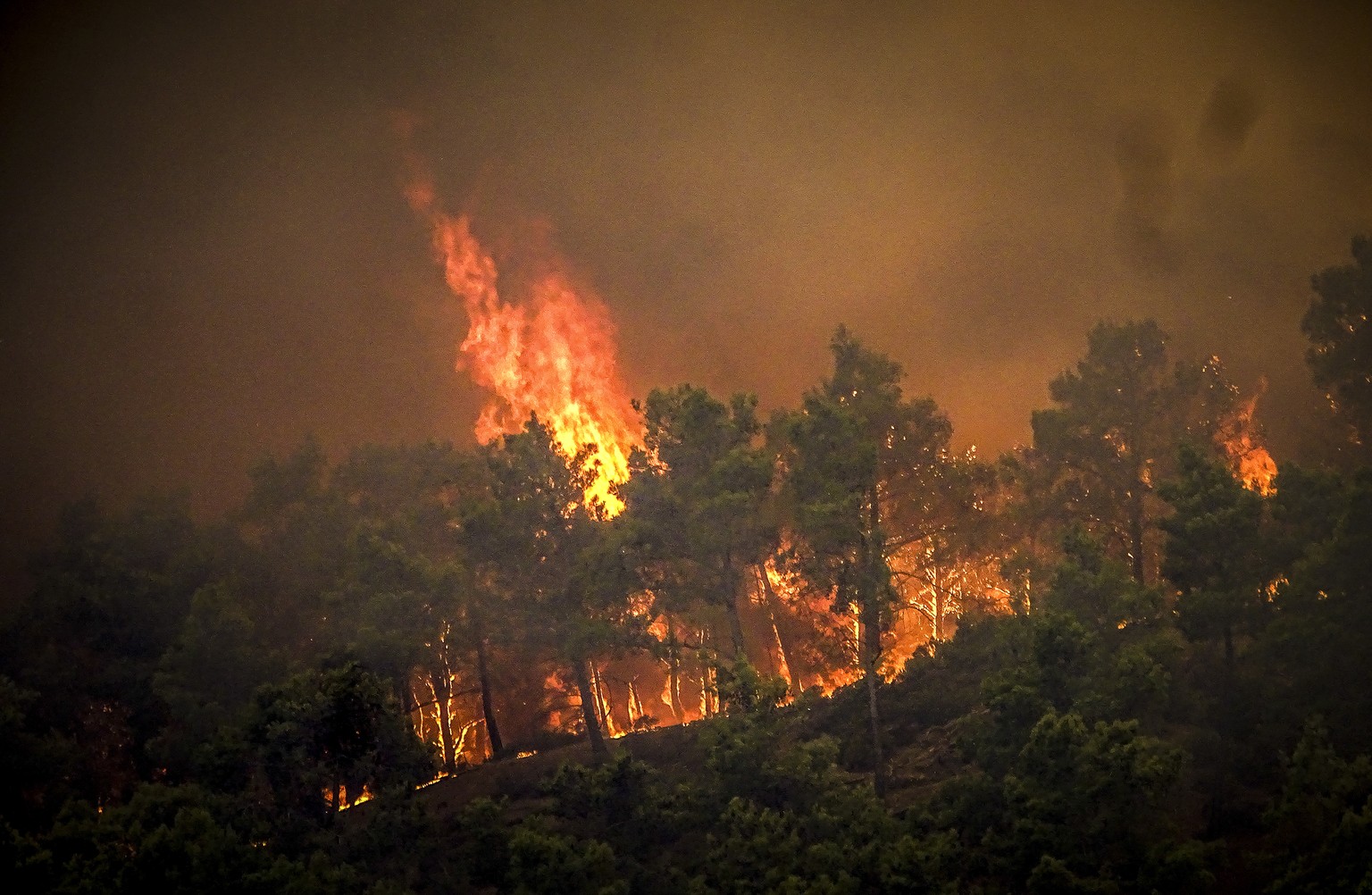 Flames rise during a forest fire on the island of Rhodes, Greece, Saturday, July 22, 2023. A large wildfire burning on the Greek island of Rhodes for a fifth day has forced authorities to order an eva ...