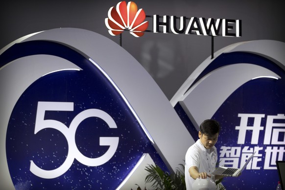 In this Sept. 26, 2018, photo, a staff member uses a laptop computer at a display for 5G wireless technology from Chinese technology firm Huawei at the PT Expo in Beijing. A spy chief said in a speech ...
