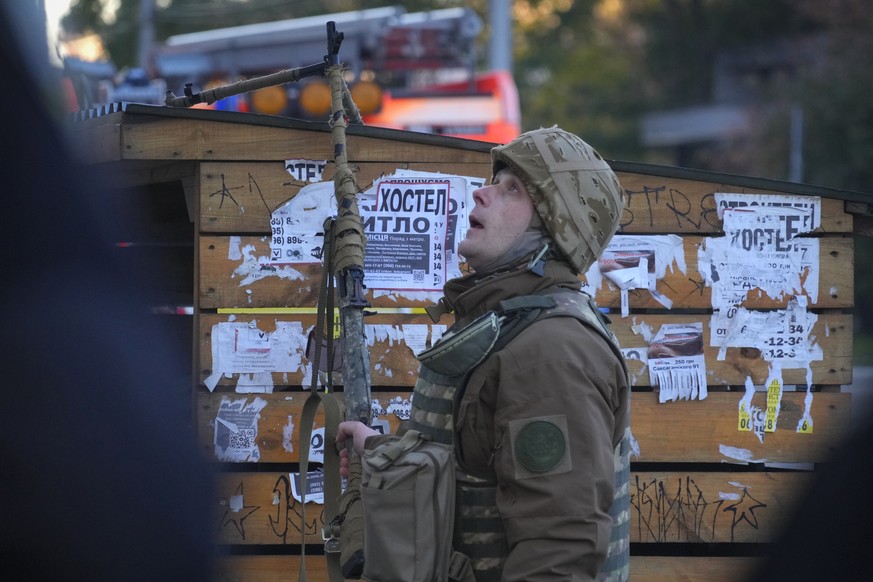 A Ukrainian soldier looks on as a drone appears in the sky seconds before it fired on buildings in Kyiv, Ukraine, Monday, Oct. 17, 2022. (AP Photo/Efrem Lukatsky)