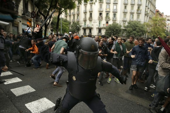 Spanish riot police swings a club against would-be voters near a school assigned to be a polling station by the Catalan government in Barcelona, Spain, Sunday, Oct. 1, 2017. Spanish riot police have f ...