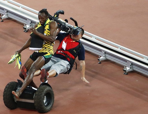 epa04990562 YEARENDER AUGUST 2015 ..A Tv cameraman drives into Usain Bolt of Jamaica after the men's 200m final during the Beijing 2015 IAAF World Championships at the National Stadium, also know ...