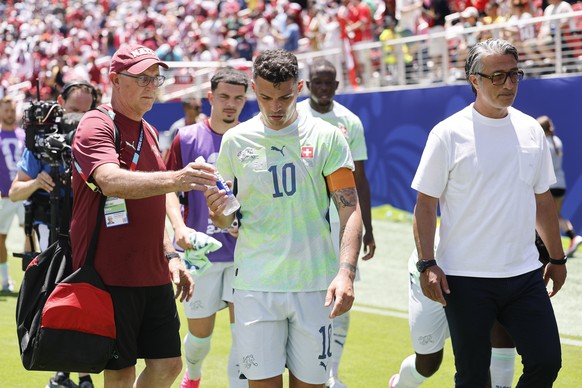 Switzerland's Granit Xhaka, center, and head coach Murat Yakin, right, leave the pitch in the halftime during the World Cup Group B soccer match between Qatar and Switzerland at the San Francisco ...