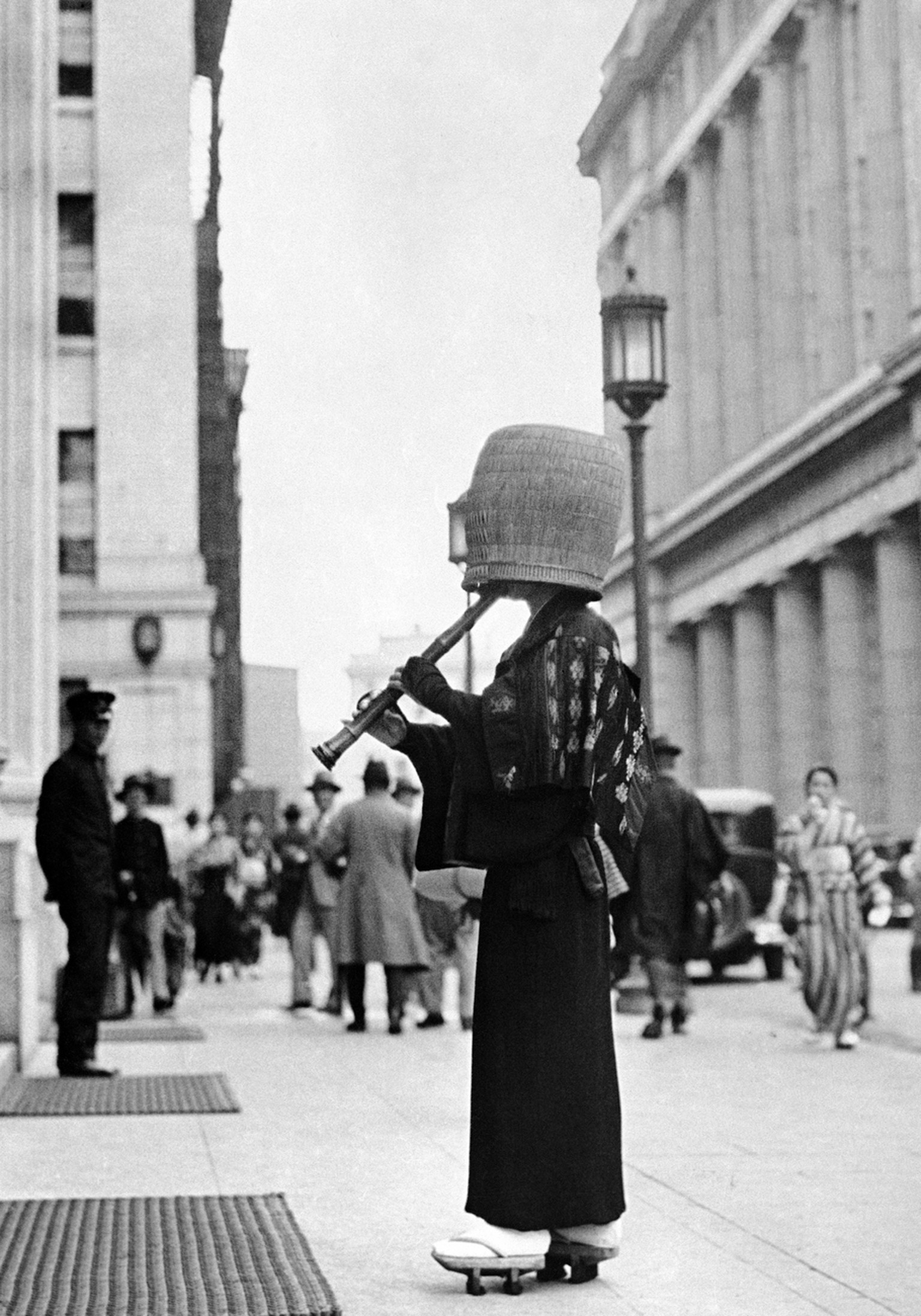 A strolling flute player in the streets of Tokyo on Jan. 19, 1937, who wear basketlike hats completely hiding their features. They never utter a word but play their flutes before the doors of homes un ...