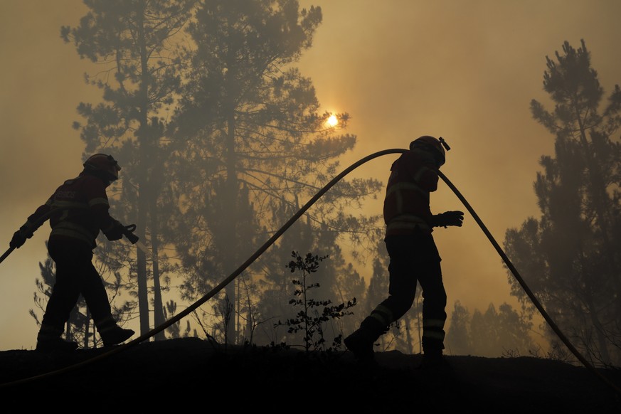 epa10064271 The silhouette of a firefighters battling a fire in Cruzinha, Alvaiazere, Portugal, 10 July 2022. The fire that has been burning in forest stands since 07 July in Cumeada, Ourem, remains a ...