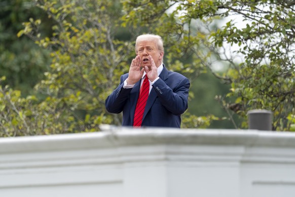 President Donald Trump shouts to reporters as he surveys the grounds from the roof above the Colonnade that goes to the West Wing of the White House, Tuesday, Aug. 5, 2025, in Washington. (AP Photo/Al ...