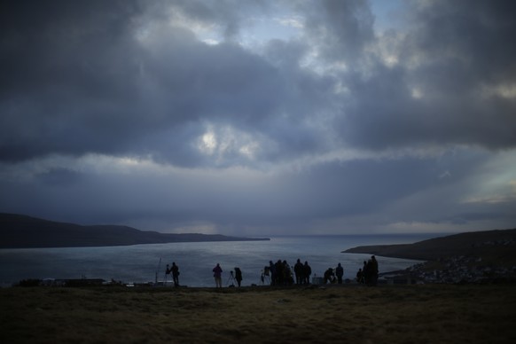 People wait for the start of a total solar eclipse from a hill beside a hotel overlooking the sea and Torshavn, the capital city of the Faeroe Islands, Friday, March 20, 2015. For months, even years,  ...