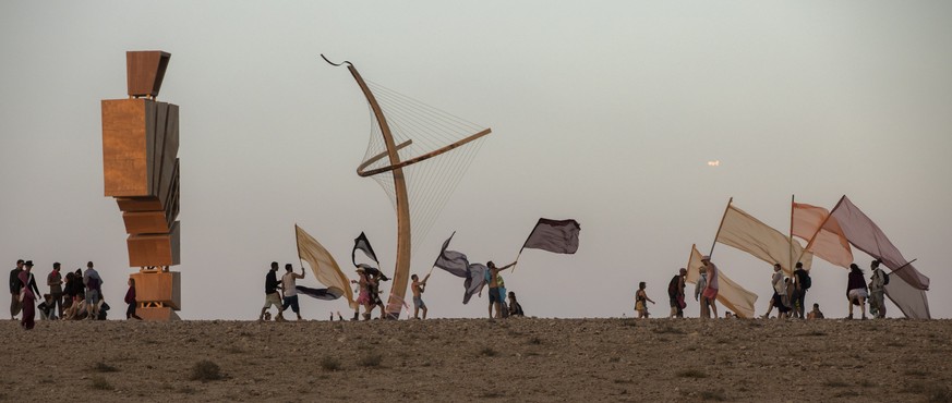 epa06740005 &#039;Burners&#039; with flags on the top of the hill where the main art installation called the &#039;Effigy&#039; depicting man and woman (R) in the Israeli MidBurn festival, near Sde Bo ...