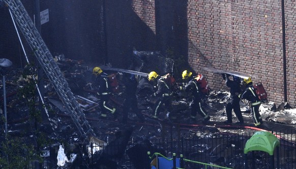 epa06027336 Firemen work at the scene to battle a fire at the Grenfell Tower, a 24-storey apartment block in North Kensington, London, Britain, 14 June 2017. According to the London Fire Brigade (LFB) ...