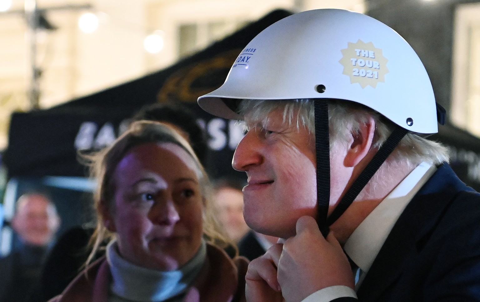 epa09613395 British Prime Minister Boris Johnson prepares to take off his helmet after riding on a bicycle around Christmas market outside 10 Downing Street in London, Britain, 30 November 2021. EPA/A ...