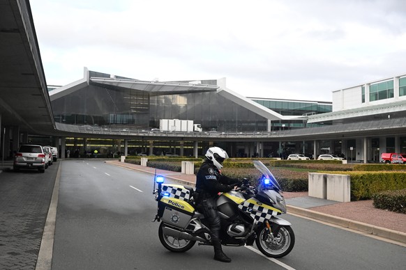 epa10120102 Australian Federal Police gather at Canberra Airport after a man fired at least three gunshots, in Canberra, Australia, 14 August 2022. The airport was evacuated and a man was arrested in  ...