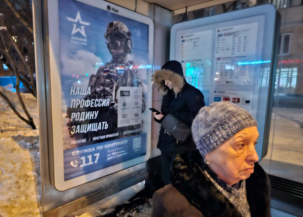 Les passagers à Moscou attendent le bus. À l'arrêt se trouve une affiche publicitaire de l'armée pour les opérations en Ukraine.