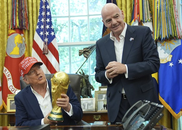 President Donald Trump holds the FIFA World Cup Winners Trophy as FIFA President Gianni Infantino looks on during an announcement in the Oval Office of the White House, Friday, Aug. 22, 2025, in Washi ...