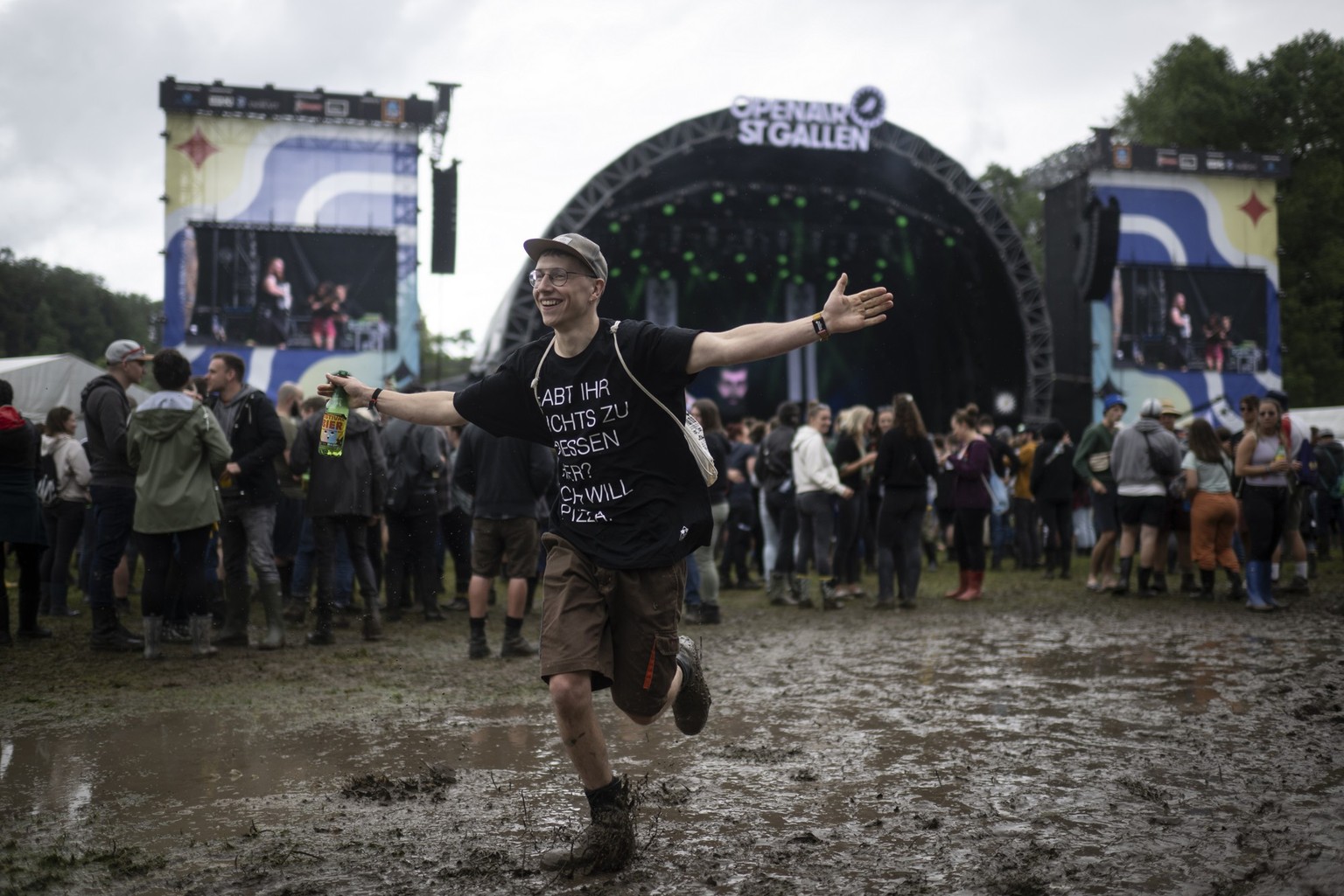 A spectator runs trough the mud in front of the main stage at the Openair St. Gallen, on Friday, July 1, 2022, in St. Gallen. The festival will take place until Sunday, July 3, 2022. (KEYSTONE/Gian Eh ...