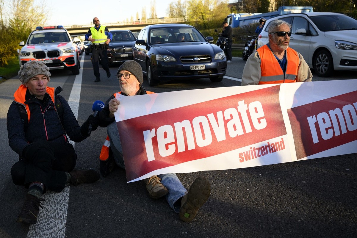Climate activist sit down in the road during the "Renovate Switzerland" a roadblock action, A1a freeway, in Lausanne, Switzerland, Monday, April 11, 2022. (KEYSTONE/Laurent Gillieron)