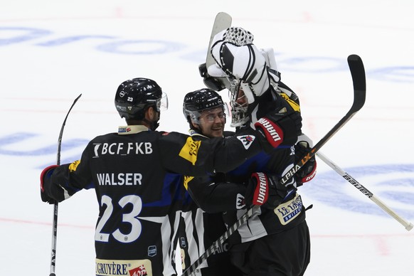 Gotterons Samuel Walser, Gotterons Nathan Marchon, und Gotterons Torhueter Reto Berra, von links, jubeln nach dem Sieg (5-3), beim Eishockey Meisterschaftsspiel der National League A zwischen den HC F ...