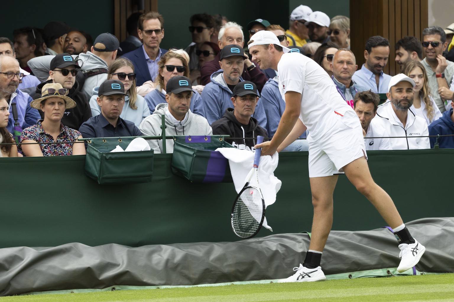 Dominic Stricker of Switzerland uses his towell beside his fans during his first round match against Alexei Popyrin of Australia at the All England Lawn Tennis Championships in Wimbledon, London, Wedn ...