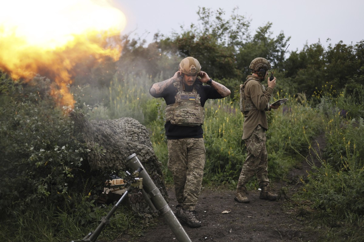 A Ukrainian servicemen of the 3rd separate assault brigade speaks on the radio while another serviceman is firing 82mm mortar towards Russian positions at the frontline near Bakhmut, Donetsk region, U ...