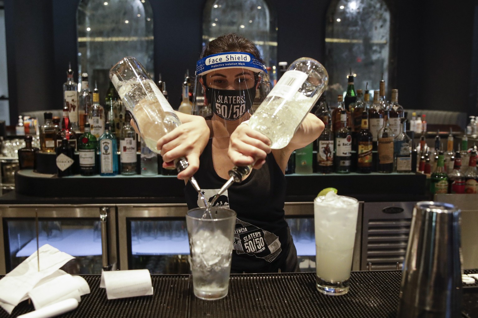 A bartender mixes a drink while wearing a mask and face shield at Slater's 50/50 Wednesday, July 1, 2020, in Santa Clarita, Calif. California Gov. Gavin Newsom has ordered a three-week closure of bars ...