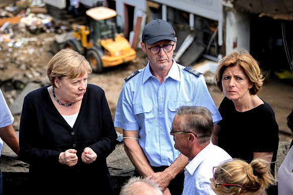 epa09351667 German Chancellor Angela Merkel (L) and Rhineland-Palatinate Prime Minister Malu Dreyer (R) inspect the damage after heavy flooding of the river Ahr caused severe destruction in the villag ...