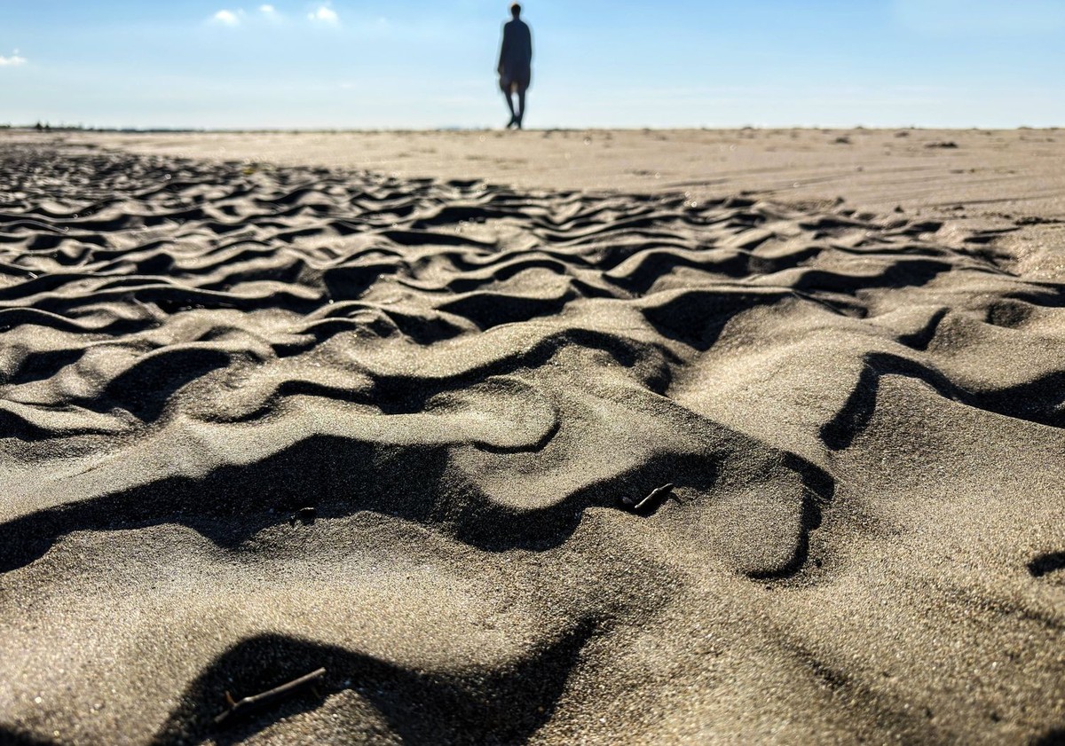 Wave ripples during low tide at the sea side of the Adriatic Sea in Gjiri i Lalzit, Albania A man walks during low tide on a beach with the sand exposed in wave formations on the Adriatic Sea in Gjiri ...