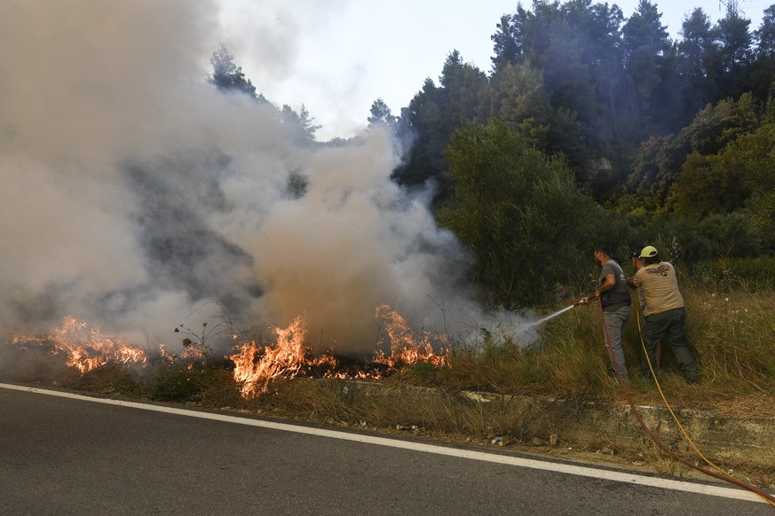 A Volonteer uses a hose to extinguish the fire near the village of Krestena south of Ancient Olympia, about 320 kilometers (200 miles) southwest of Athens, as authorities evacuate urgently another fiv ...