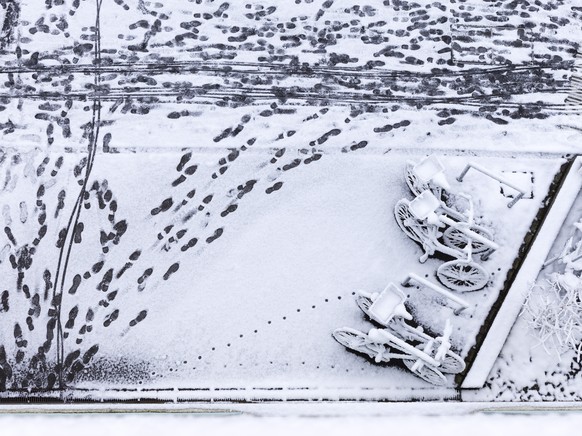Verschneite Fahrraeder und Fussspuren im Schnee vor einem Wohnhaus in Zuerich Wipkingen, fotografiert am Freitag, 19. Januar 2024. (KEYSTONE/Christian Beutler)