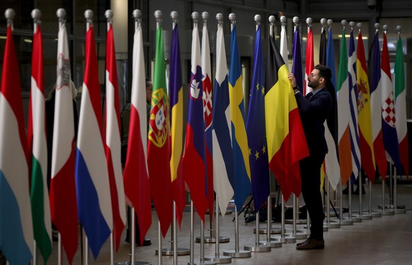epa11028215 A worker puts the finishing touches to an exhibition of EU member state flags ahead of a European Council in Brussels, Belgium, December 14, 2023. EU leaders meet in Brussels for a pair of ...