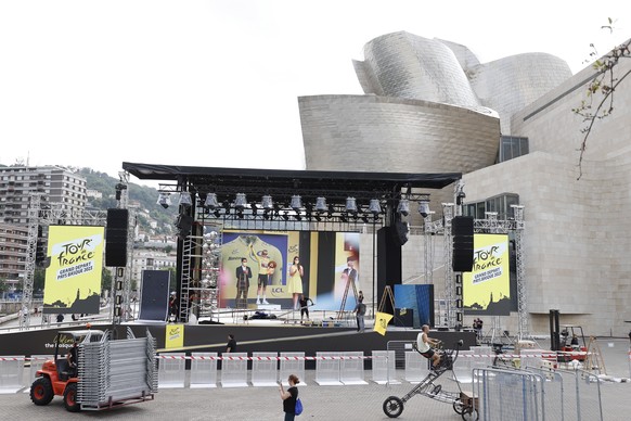 epa10715150 Several workers prepare the big stage fort the presentation of the cycling teams are seen on the eve of the event next to the Guggenheim Museum of Bilbao, Spain, 28 June 2023. Bilbao will  ...