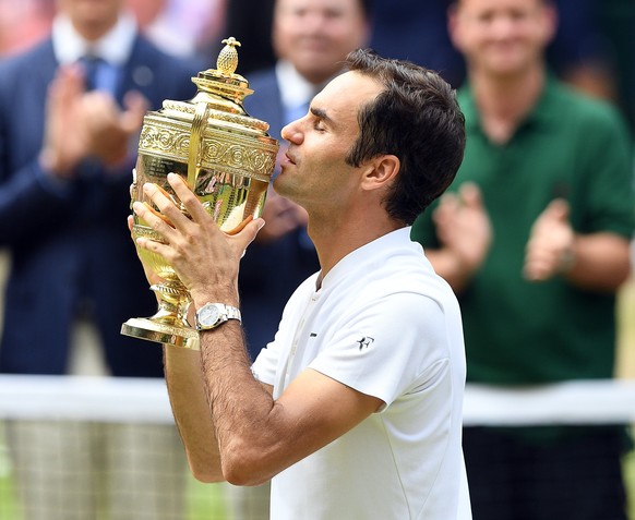 epa06091246 Roger Federer of Switzerland kisses the championship trophy following his victory over Marin Cilic of Croatia in the men&#039;s final of the Wimbledon Championships at the All England Lawn ...