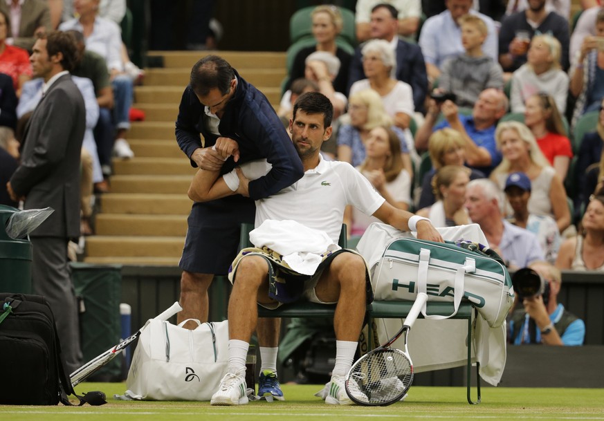 Serbia&#039;s Novak Djokovic receives treatment from a trainer during a break in his Men&#039;s Singles Match against Adrian Mannarino of France on day eight at the Wimbledon Tennis Championships in L ...