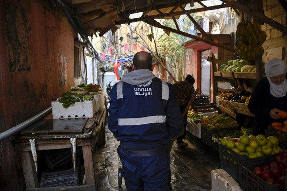 epa11171865 A Palestinian refugee from the sanitary department of the United Nations Relief and Work Agency (UNRWA) walks at an alley at the Palestinian refugee camp of Mar Elias in Beirut, Lebanon, 2 ...