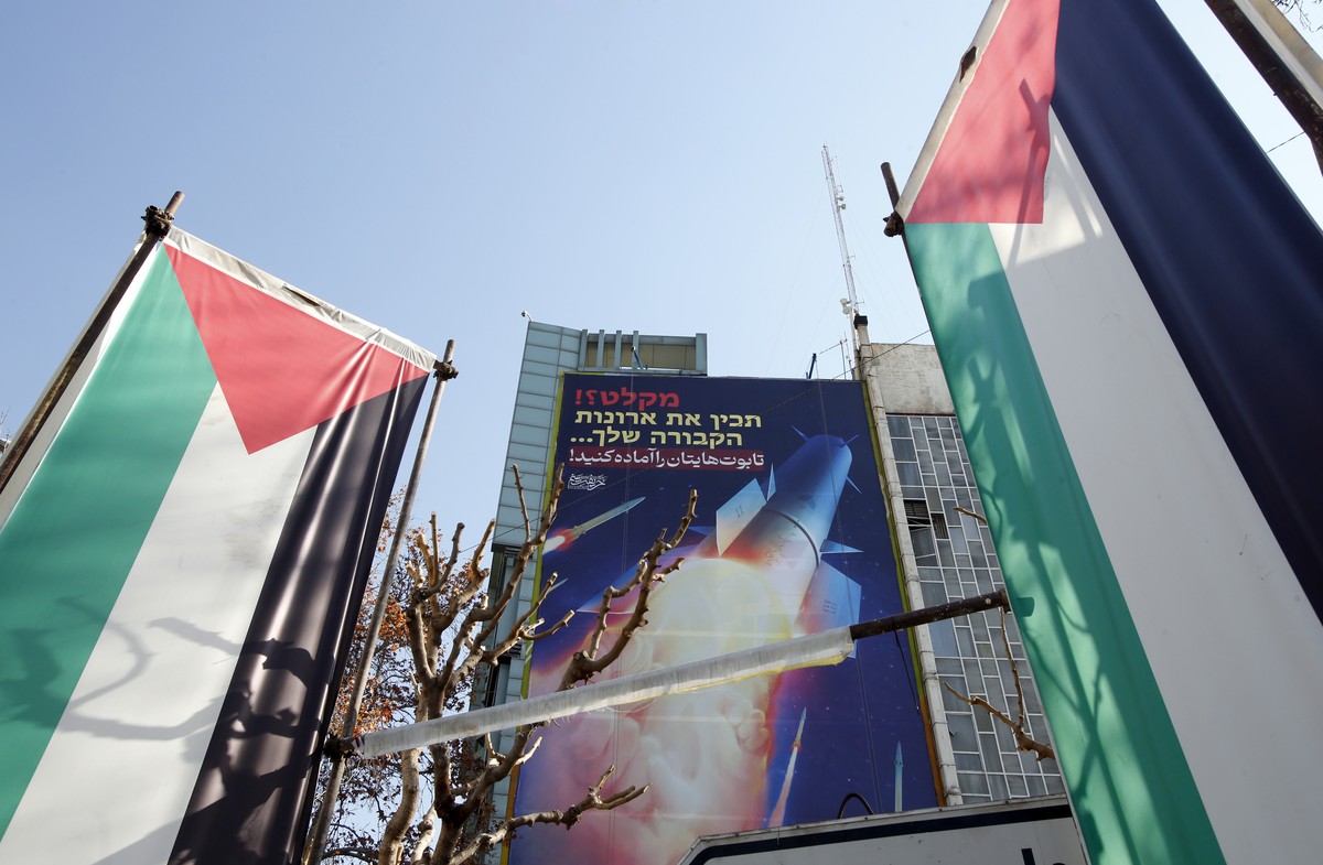 epa11082355 Palestinian flags and a billboard depicting Iranian missiles with a message in Persian and Hebrew reading: 'prepare your coffins', hangs on a building at Palestine square in Tehr ...