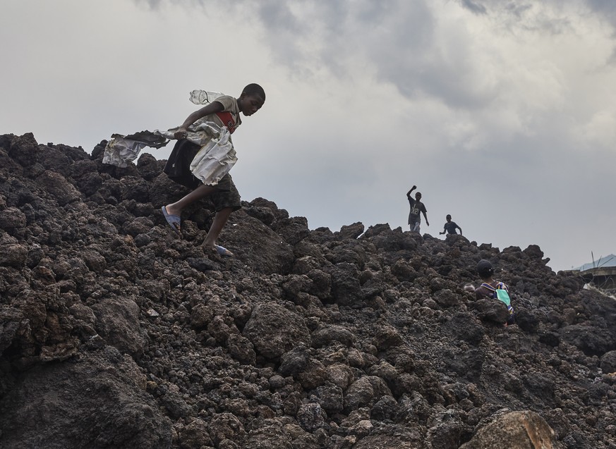 epa09227833 Congolese street children in the neighbourhood of Buhene play on piles of lava in the aftermath of a volcanic eruption in Goma, Democratic Republic of Congo, 25 May 2021. One of the planet ...