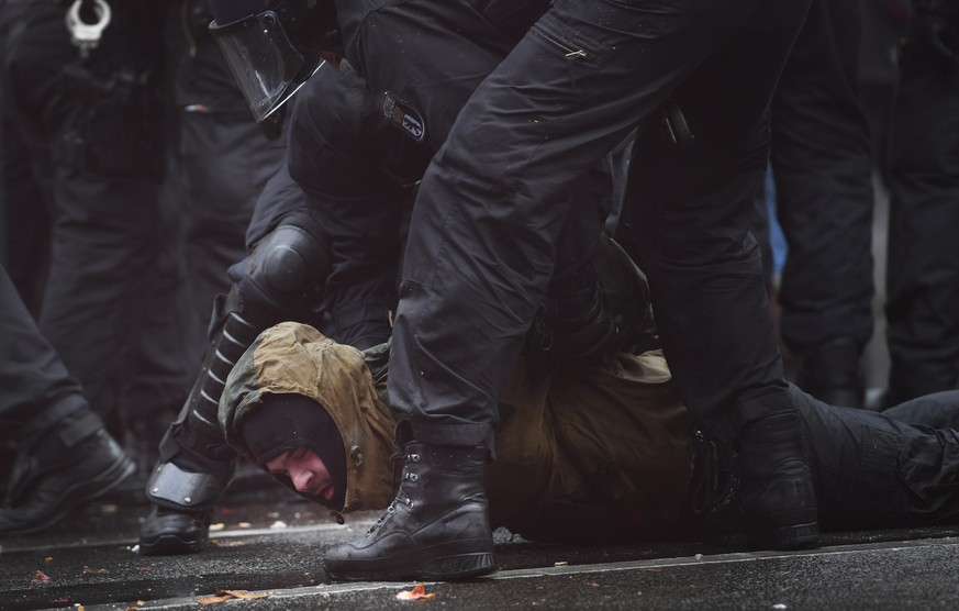 epa08827233 Riot police detain a protester while attempting to break up a demonstration against German coronavirus restrictions in front of the Brandenburg Gate in Berlin, Germany, 18 November 2020. W ...