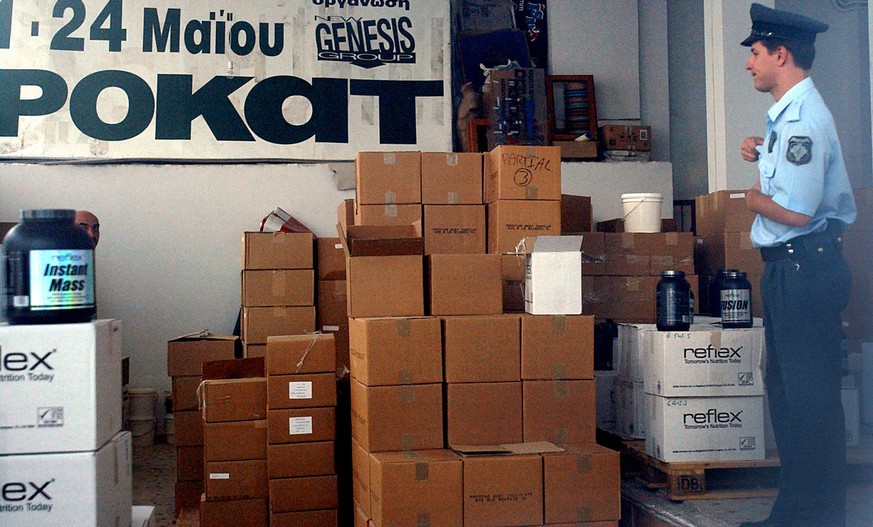 A Policeman stands in front of boxes with nutritional supplements at a warehouse owned by Greek sprint coach Costas Tsekos in Athens on Friday, Aug. 20, 2004. Authorities inspected the site after Gree ...
