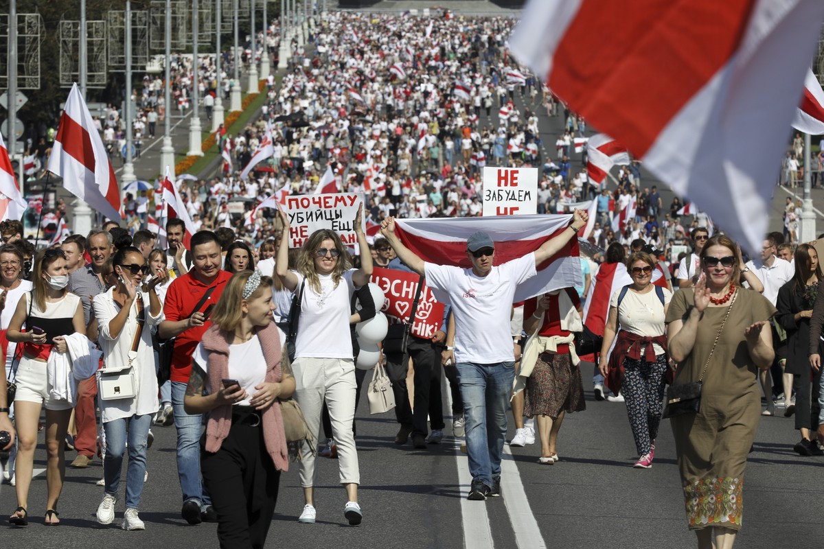 Belarusian opposition supporters with old Belarusian national flags and a poster reading "Why haven't the killers been arrested yet?" rally in Minsk, Belarus, Sunday, Aug. 30, 2020. Ten ...