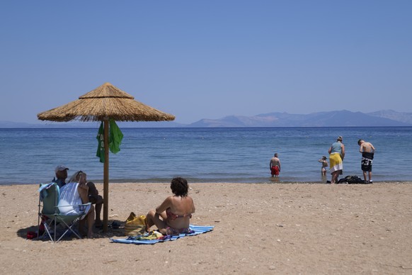 People enjoy the sea in Rafina town, east of Athens, Greece, Friday, July 22, 2022. Many parts of the country are already reaching temperature highs of 39 to 40 degrees Celsius (102.2 to 104 Fahrenheit) and expected to persist at least until the end of the month. (AP Photo/Thanassis Stavrakis)