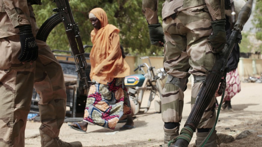 FILE - In this file photo from Wednesday, April 8, 2015, a woman walks past Nigerian soldiers at a checkpoint in Gwoza, Nigeria, a town recently liberated from Boko Haram.  Nigerian troops have driven out Boko Hara...
